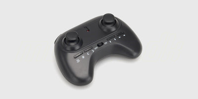 Drone Super Glow mini-drone med blåt LED-lys i en beskyttende ramme svævende over en hånd.