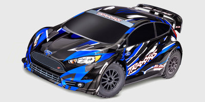 Traxxas Ford Fiesta ST Rally Brushless fjernstyret bil i blå og hvid med dæk i hurtig fart på grus.