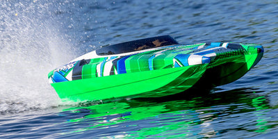 Hurtiggående orange og sort DCB M41 Widebody Catamaran fjernstyret båd i aktion på vandet.