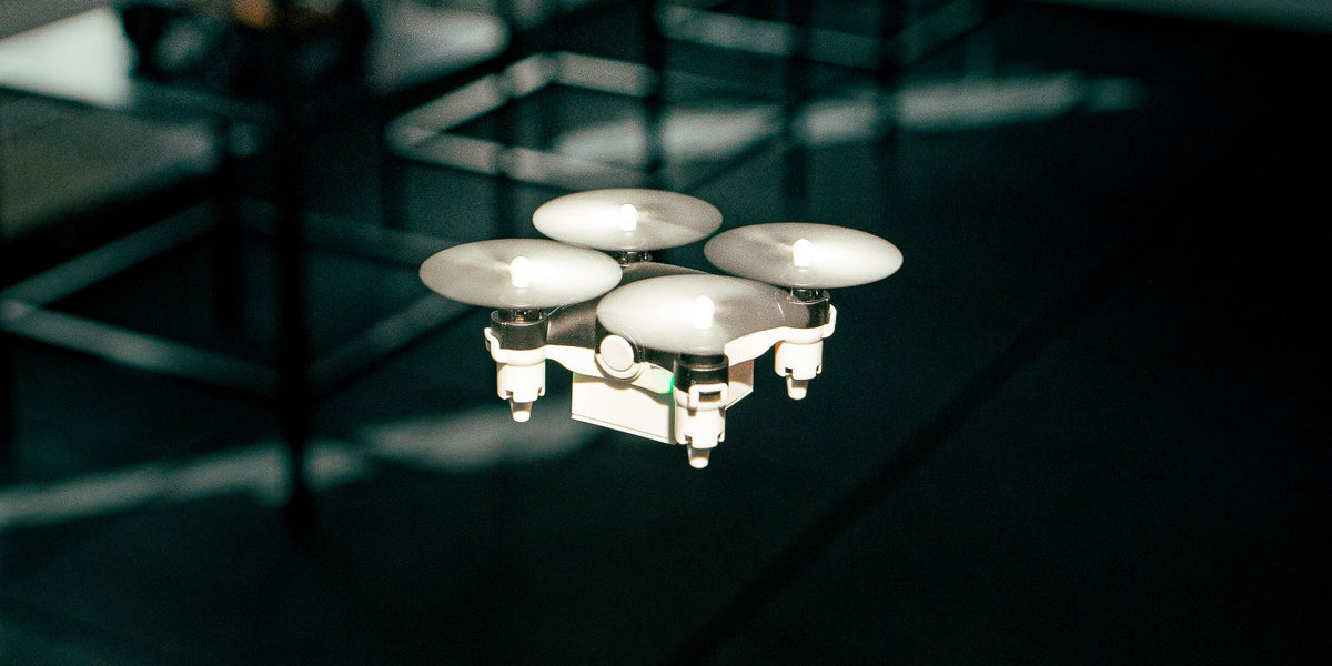 Sort Micro Drone i luften i et mørkt rum