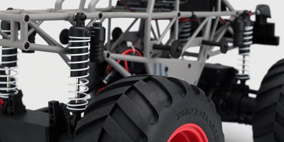 Robust Quakeshock monster truck i rød og hvid med store offroad dæk vist fra siden på hvid baggrund.